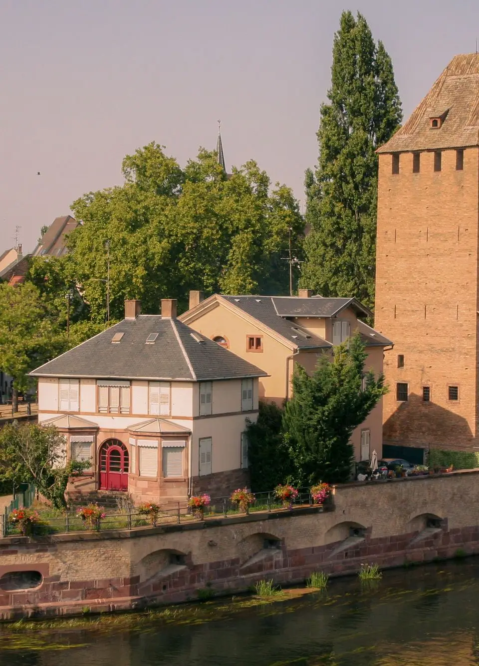 Beautiful view of a medieval tower and garden by the water in Strasbourg.