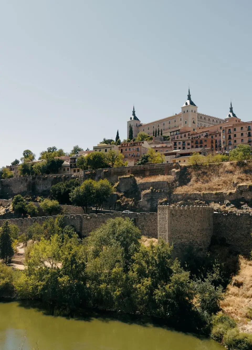 Scenic view of Toledo's historic Alcázar and surrounding landscape on a sunny day.