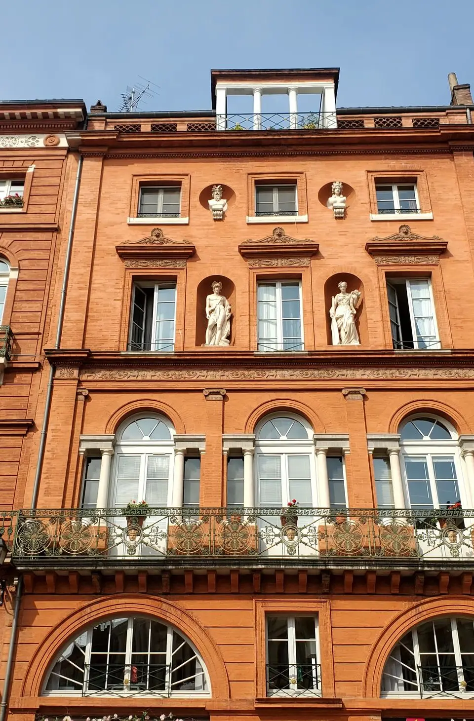 Red brick facade with classical architecture in Place de la Trinité, Toulouse.