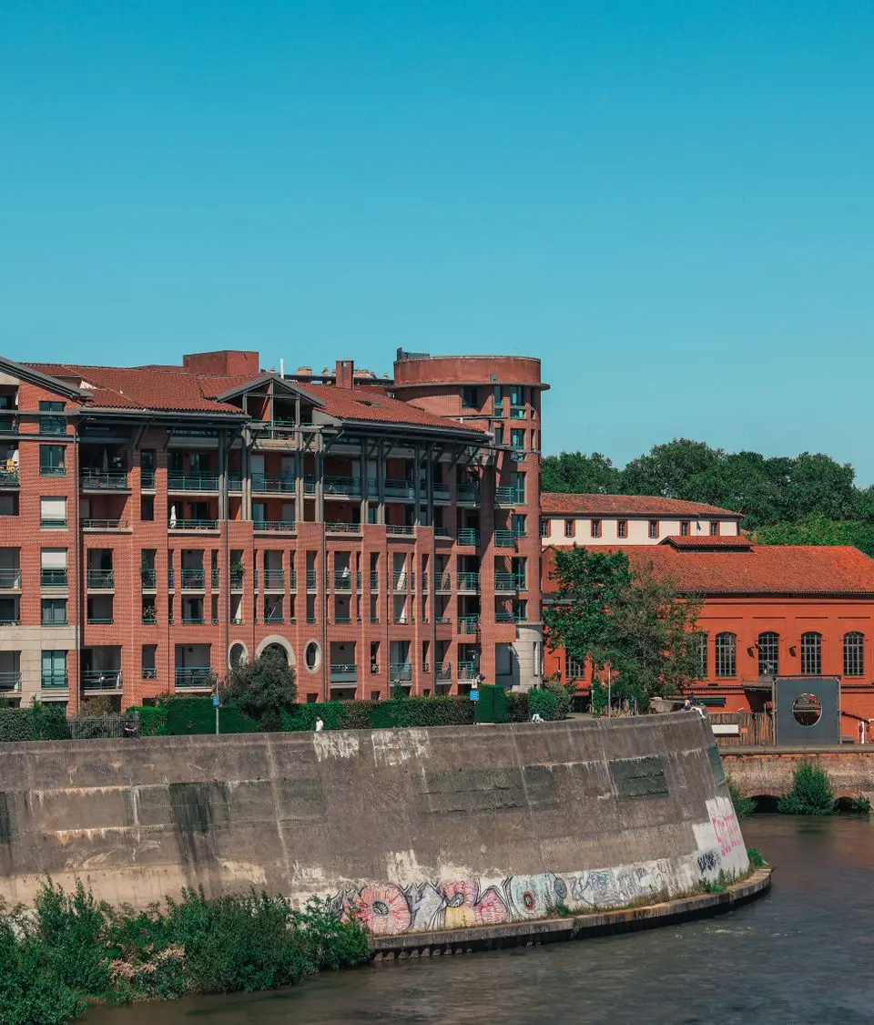 A picturesque view of brick buildings along the river in Toulouse, Occitanie, France.