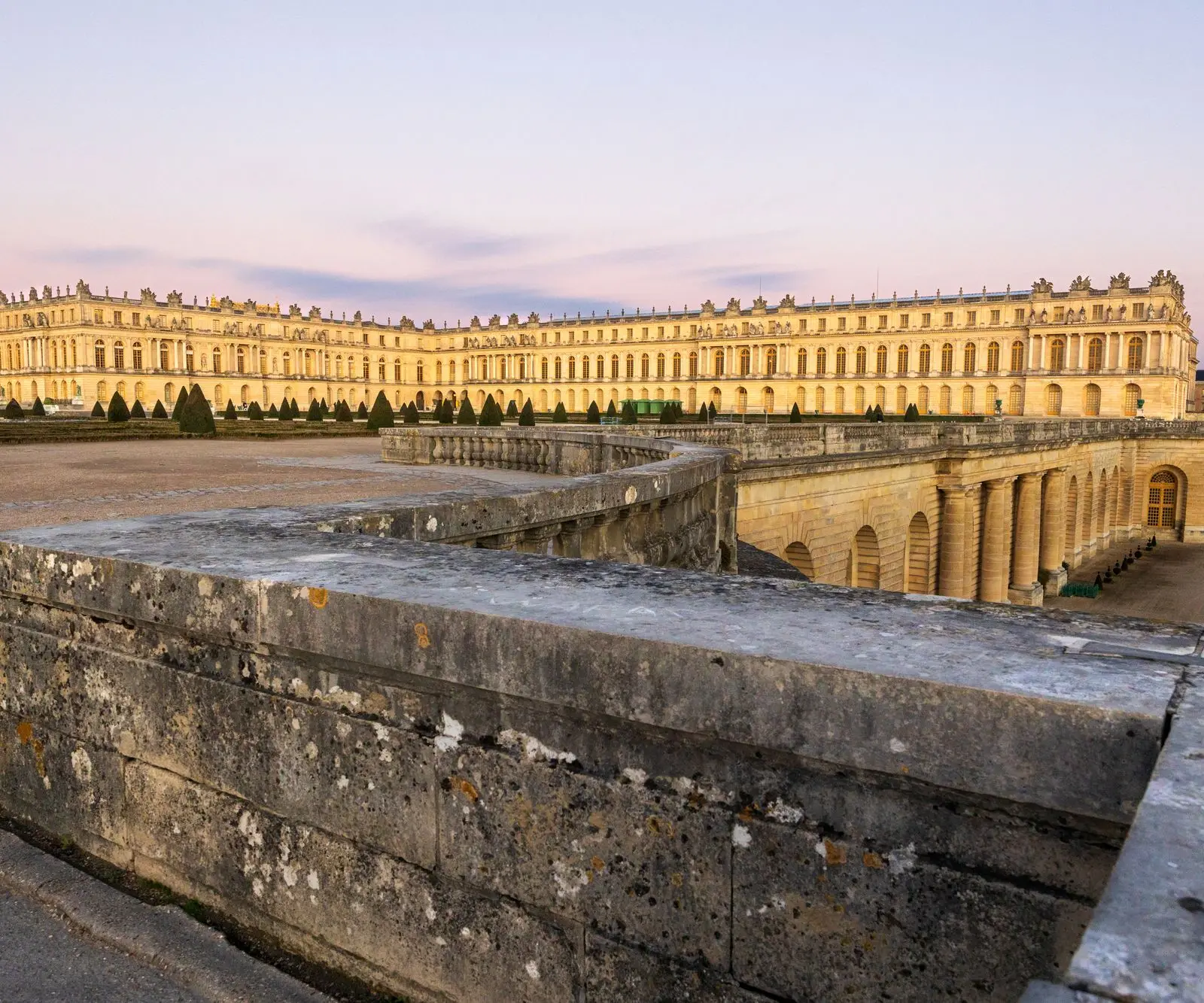 Stunning view of the Palace of Versailles at sunset, highlighting its architectural grandeur.