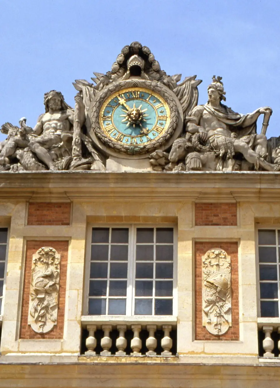 Close-up of ornate clock and sculptures on the facade of the Palace of Versailles, France.