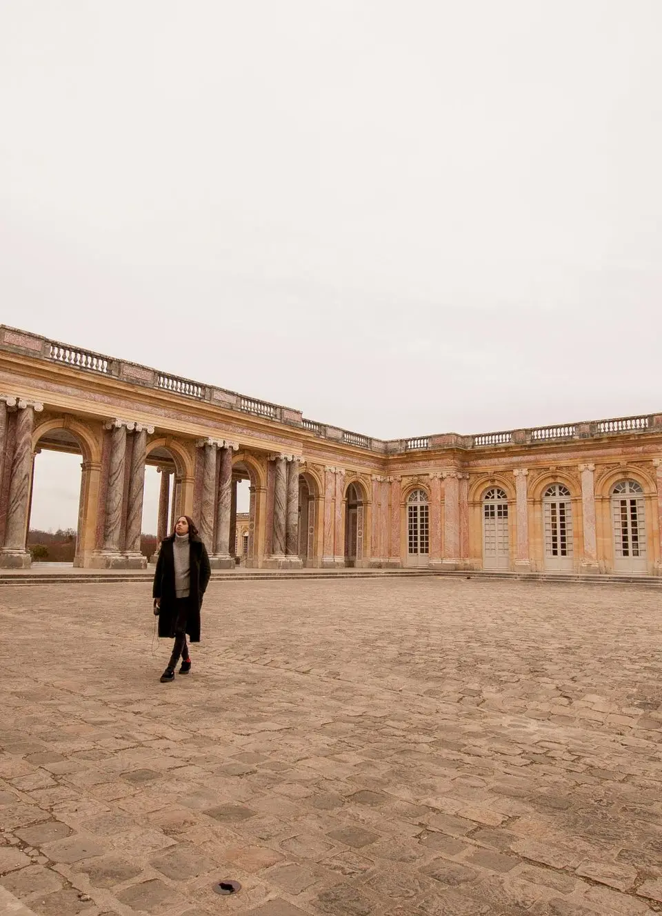 A woman walks through the historic courtyard of the Grand Trianon Palace in Versailles, France.